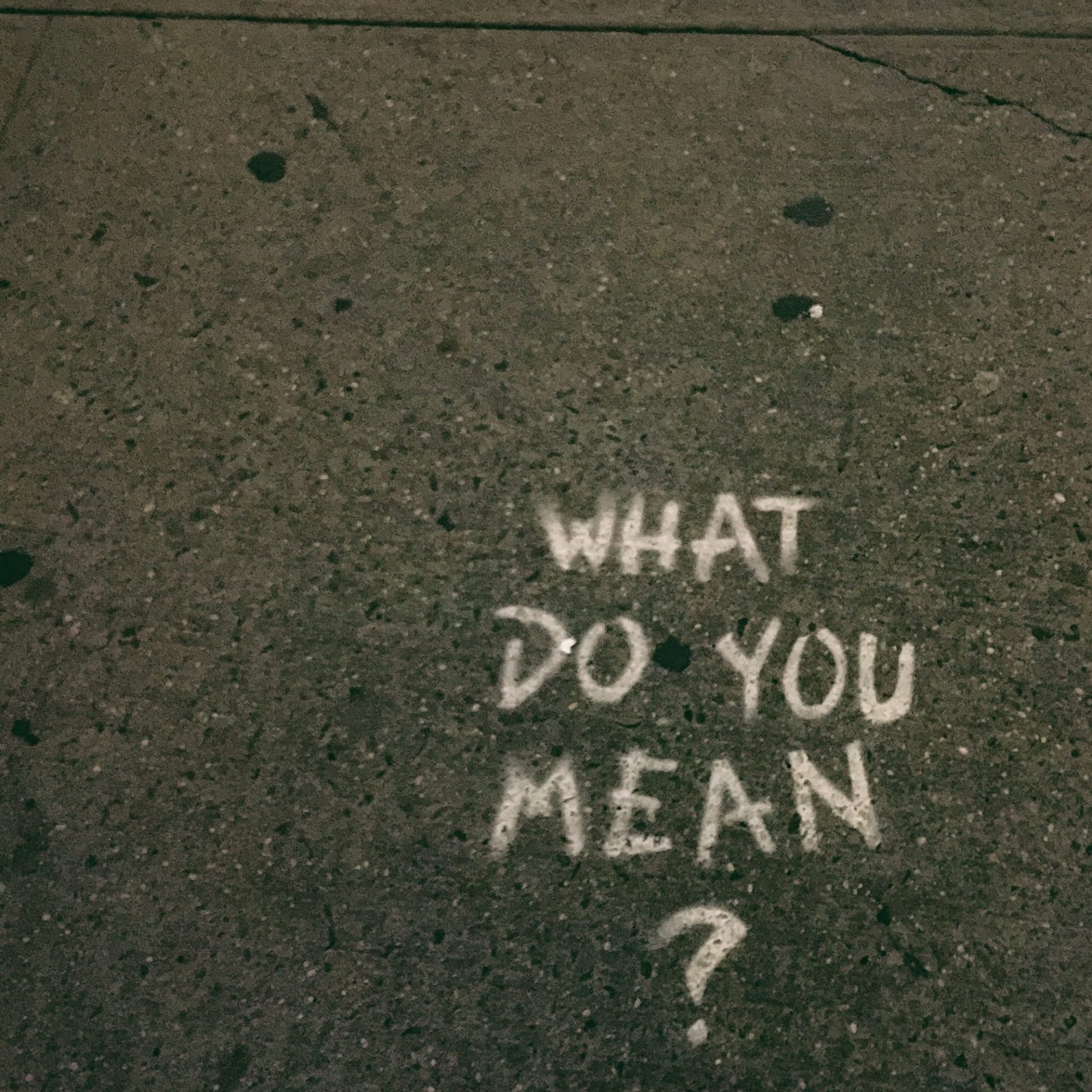 words spray painted on the floor reading 'what do you mean?'